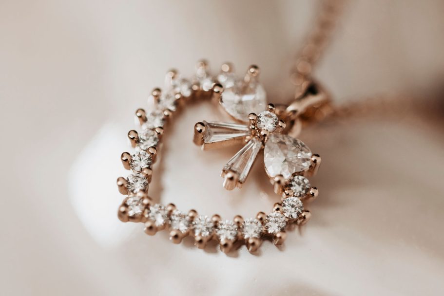 Herzförmiger Anhänger aus Rosegold mit Zirkonia-Steinen und einer kleinen Schleife.