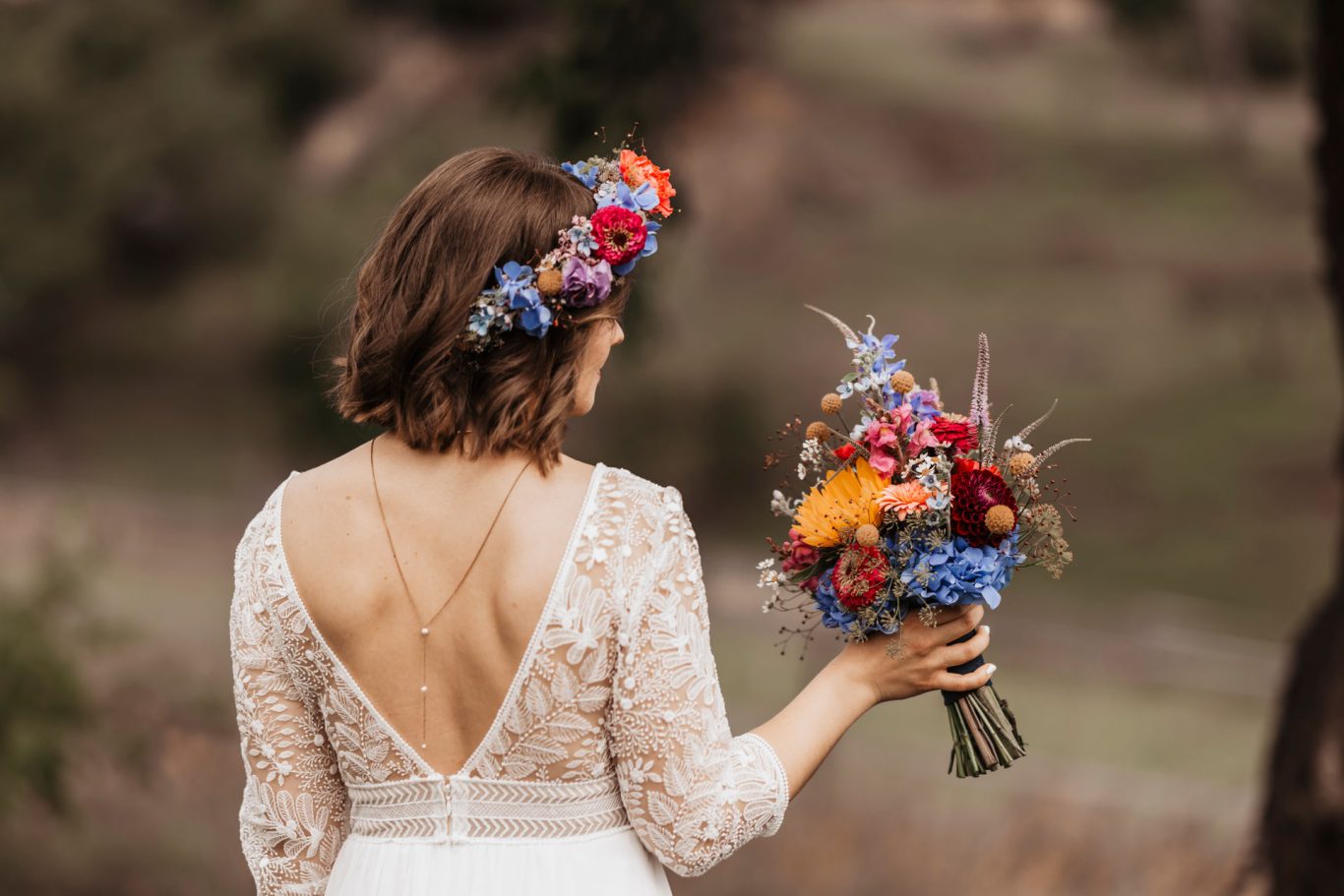 Hochzeitsbraut mit blumiger Haarschmuck und buntem Blumenstrauß.
